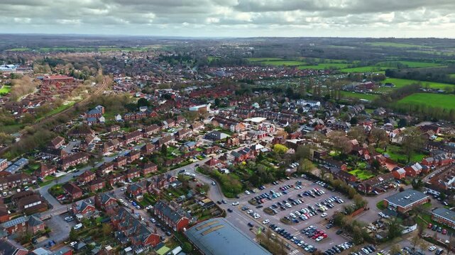aerial drone landscape shot over Romsey, Hampshire, England Town village in spring sunset surrounded by nature trees and fields with golden warm light above. Calm quiet roads and paths below