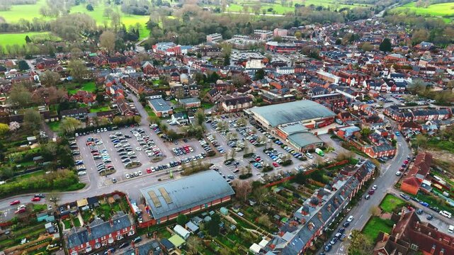aerial drone landscape shot over Romsey, Hampshire, England Town village in spring sunset surrounded by nature trees and fields with golden warm light above. Calm quiet roads and paths below