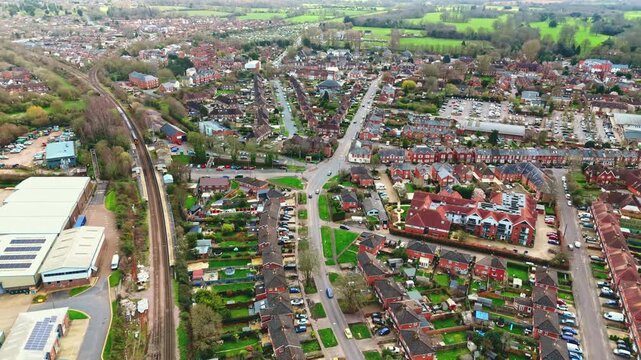 aerial drone landscape shot over Romsey, Hampshire, England Town village in spring sunset surrounded by nature trees and fields with golden warm light above. Calm quiet roads and paths below