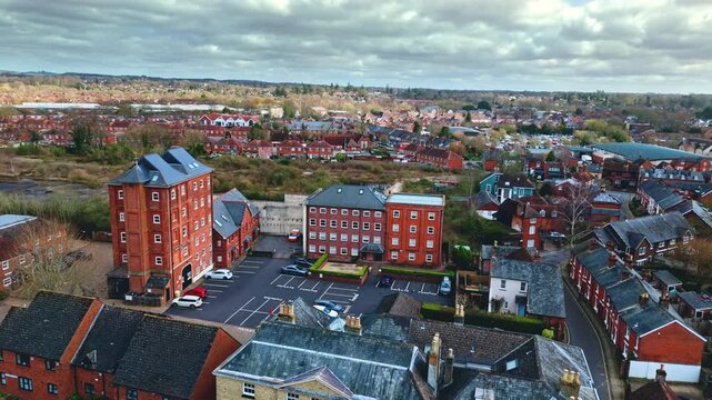 aerial drone landscape shot over Romsey, Hampshire, England Town village in spring sunset surrounded by nature trees and fields with golden warm light above. Calm quiet roads and paths below