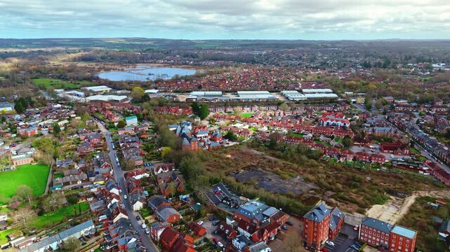 aerial drone landscape shot over Romsey, Hampshire, England Town village in spring sunset surrounded by nature trees and fields with golden warm light above. Calm quiet roads and paths below