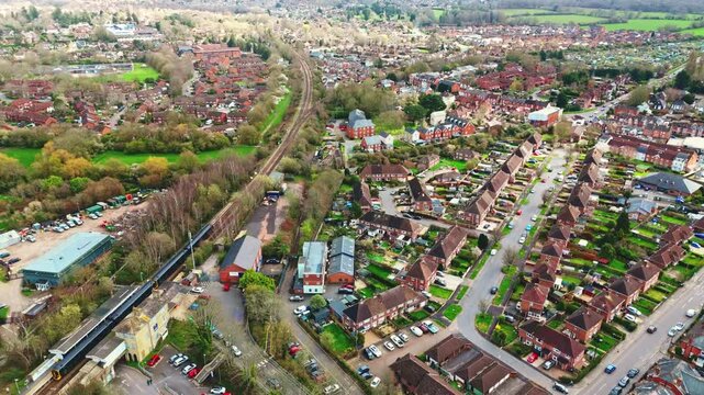 aerial drone landscape shot over Romsey, Hampshire, England Town village in spring sunset surrounded by nature trees and fields with golden warm light above. Calm quiet roads and paths below