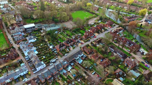 aerial drone landscape shot over Romsey, Hampshire, England Town village in spring sunset surrounded by nature trees and fields with golden warm light above. Calm quiet roads and paths below