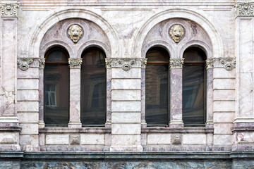 Fototapeta premium Two arched windows with a column and a bas-relief on a wall made of marble slabs. From the Windows of the world series.