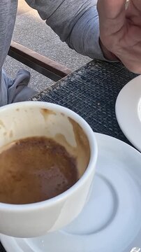 A Relaxing Moment Enjoying Coffee: Savoring Espresso at a Casual Cafe with a Simple Plate in the Background