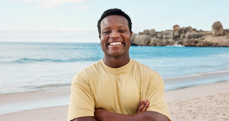Travel, portrait and man with arms crossed at beach, confident and happy on summer holiday or space. Ocean, vacation and black person with smile on weekend break, tourism and adventure in Nigeria