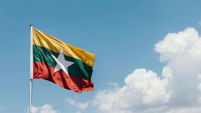 The Myanmar flag waves proudly against a bright blue sky with fluffy white clouds, captured in a medium shot with a clear focus on the national symbol and a serene atmosphere