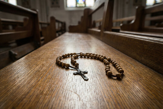Rosary beads placed on wooden church pew in solemn setting  