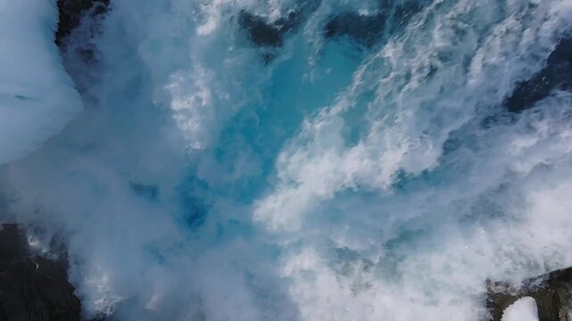 Tele top down static shot of icy blue Bruarfoss - Midfoss water crashing below
