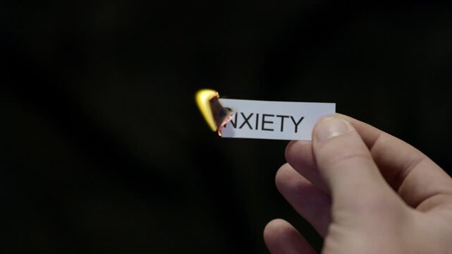 Burning Away Anxiety - Hand Setting Fire to Paper note Marked &ldquo;ANXIETY&rdquo;, Powerful Release of Criticism, Guilt and Shame, Dark Cinematic Close-Up. Mental health, therapy