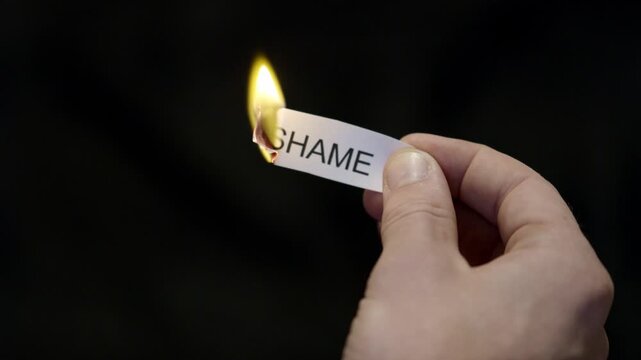 Burning Away Shame - Hand Setting Fire to Paper note Marked &ldquo;SHAME&rdquo;, Powerful Release of Criticism, Guilt and Shame, Dark Cinematic Close-Up. Mental health, therapy