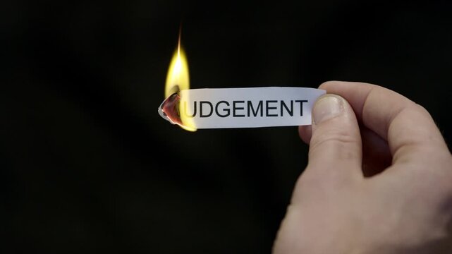 Burning Away Judgment - Hand Setting Fire to Paper note Marked &ldquo;JUDGEMENT&rdquo;, Powerful Release of Criticism, Guilt and Shame, Dark Cinematic Close-Up. Mental health, therapy