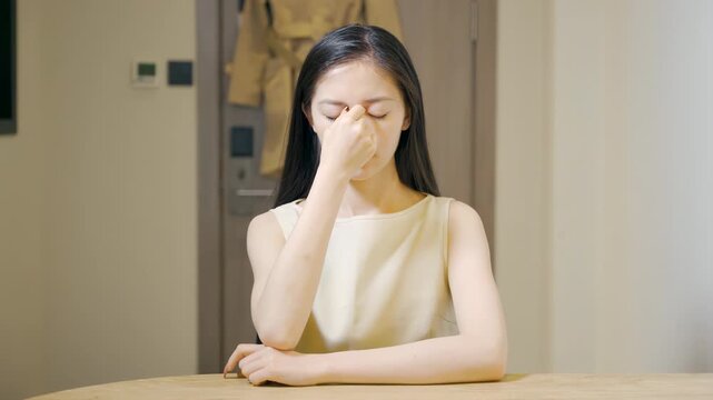 Tired overworked businesswoman feeling stressed, eye strain and overloaded digital fatigue long hours with burnout working overtime, exhausted, brain fog massaging her eyes, sustainable workplace
