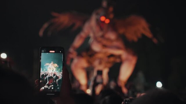 Ogoh Ogoh festival in Bali captured on smartphone by crowd at night, people recording traditional parade and ritual