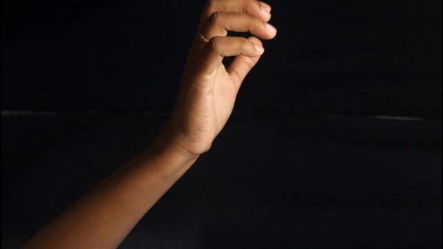 Close-up of a human hand showing different gestures against a black background. The isolated composition highlights communication, body language, and symbolic meaning of hand signs. Ideal for concepts