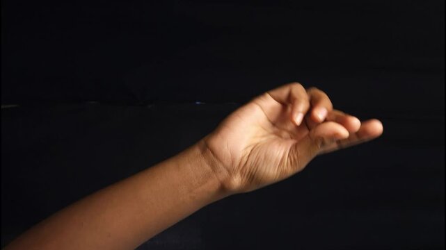Close-up of a human hand showing different gestures against a black background. The isolated composition highlights communication, body language, and symbolic meaning of hand signs. Ideal for concepts
