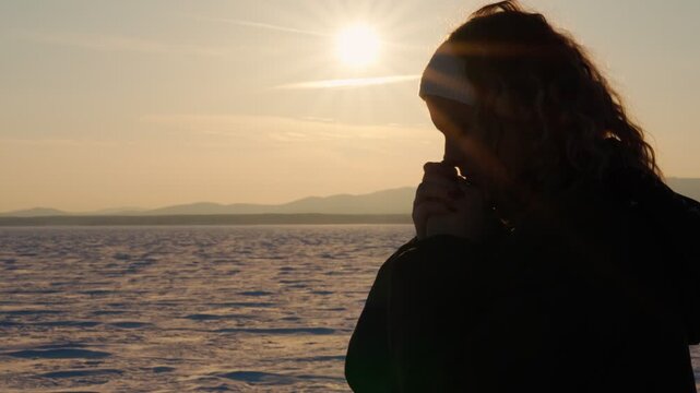 A lonely praying girl against the sunset background asks God for forgiveness and blessings for a happy life. The concept of aspiration, luck and inspiration.