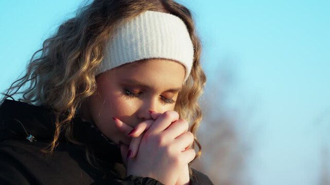 A young girl praying against the background of a blue sky asks God for forgiveness and a blessing on her life. The concept of hope, luck and inspiration.