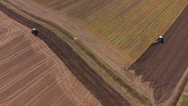 Agricultural Harmony: Two tractors diligently till vast agricultural fields, showcasing the harmonious blend of technology and nature in modern farming.