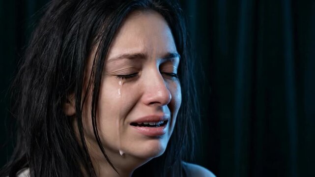 Woman with tears welling in eyes starts to cry. Emotional sadness builds as tears stream down face. Sequence captures progression from teary gaze to sobbing expression.