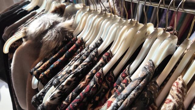 Various sweaters and vests with patterned fabrics displayed on hangers on a rack in store