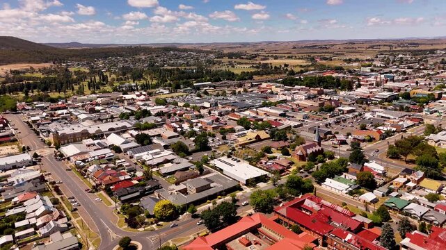 Drone over remote Australian town of Goulburn with bright midday light above buildings and trees