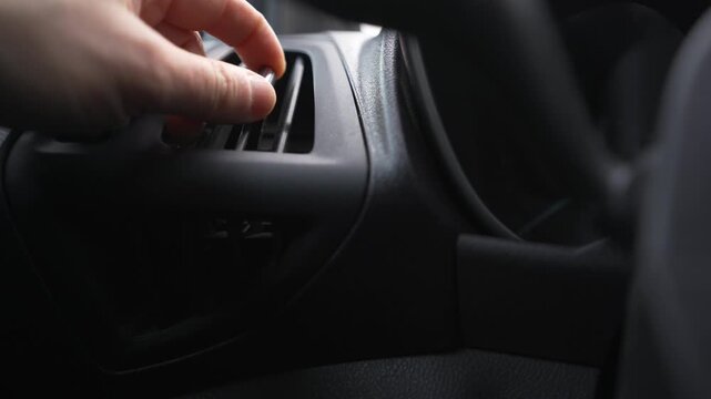 Hand adjusting air vent inside car