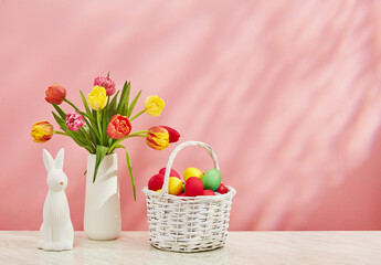 Easter basket with eggs tulips and bunny on pink background
