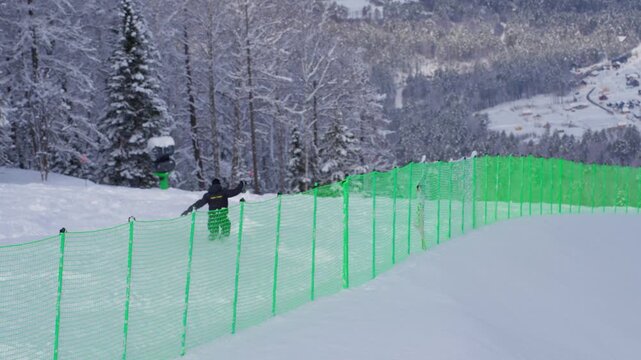 Snowy Hillside With Safety Net. Athlete Adjusts Stance After Fall. Quiet Winter Slope With Skier Near Safety Barrier. Serene Snowy Landscape Where Skier Pauses Beside Protective Green Netting