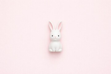 Obraz premium Cute white Easter bunny figurine on a soft pink background, minimalist style