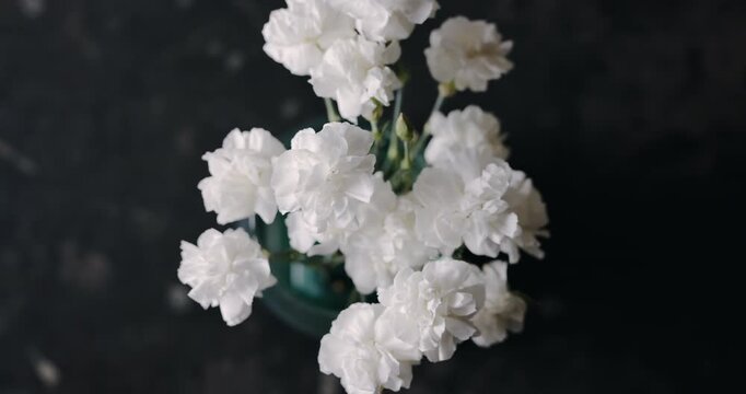 Beautiful white carnation flowers bouquet on dark background, top view