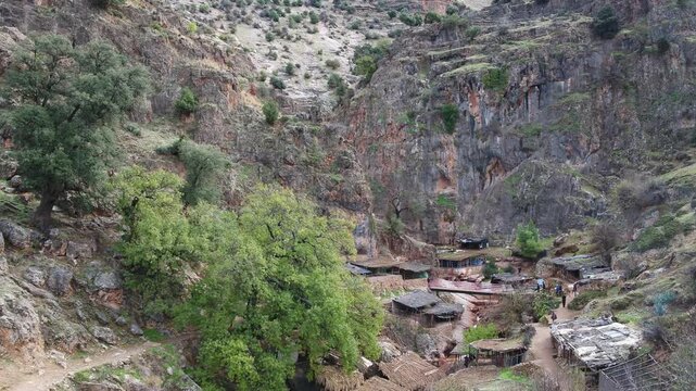 Drone view of traditional riverside cafes and small huts built along the cliffs at the Oum Er-Rbia springs near Khenifra in the Middle Atlas Mountains.