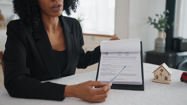 Presentation of mortgage or insurance agreement, real estate broker talking. African american woman showing papers for clients and explaining conditions of installment plan and bank credit service