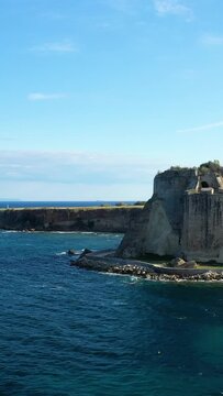 Historic stone fortress on the rocky coastline of Koroni, Greece, overlooking the deep blue sea under a clear sky.