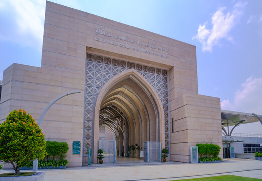 The front main entrance of the Tuanku Mizan Zainal Abidin Mosque known as Iron Mosque featuring decorative stone archway, and modern stainless steel structural elements under a blue sky.