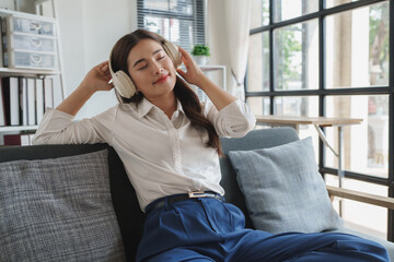 Young woman enjoying music with headphones relaxing on sofa © crizzystudio