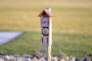 Drewniany dom dla owadów i pszczół umieszczony w ogrodzie na słupku. Hotel dla zapylaczy jako element ochrony przyrody i ekologicznego wspierania bioróżnorodności. © Henryk Niestrój