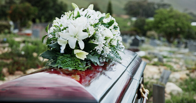 Coffin, flowers and funeral in graveyard with death, remembrance or burial ceremony for final goodbye. Casket, floral bouquet and memorial service in cemetery outdoor with honor, tribute or tradition