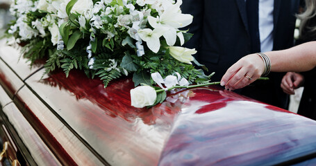 Woman, hand and rose in cemetery with coffin, funeral service and people mourning for burial...