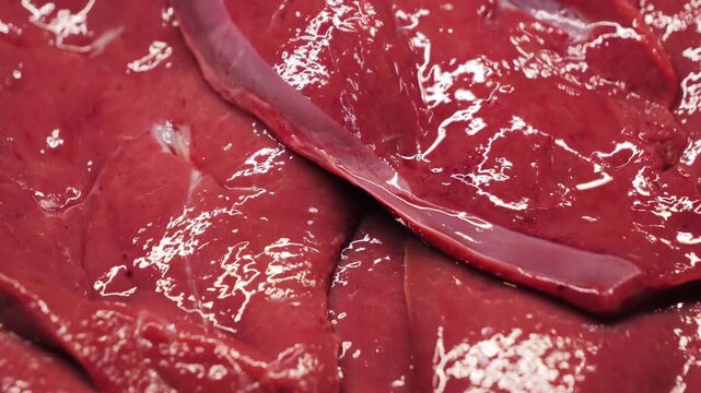 Close-up texture of raw beef liver cut into slices. Fresh organ meat prepared as steaks, detailed food texture. High quality 4k footage