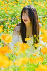 Naklejka premium Beautiful Woman Surrounded by Vibrant Spring Flowers in a Field