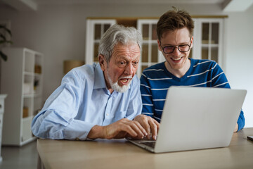 Fototapeta premium Senior man receiving technology advice from grandson