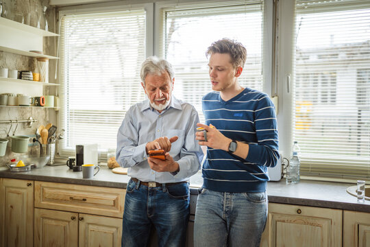 Family members discussing technology and generational differences in home kitchen