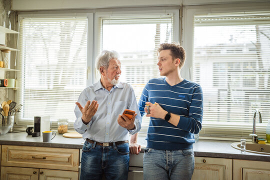 Family members discussing technology and generational differences in home kitchen