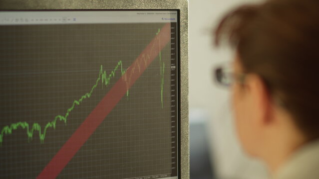 Minsk, Belarus - April 1 2020. Woman trader sitting near the monitor analyzes financial crisis, have fun and enjoy