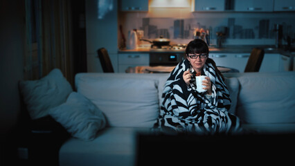 Obraz premium Woman Relaxing on Couch with Blanket Eating Ice Cream at Night, have fun and enjoy