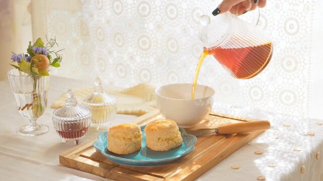 ティーポットから白いティーカップに紅茶を注ぐ女性の手元。アイレベル