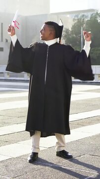 Vertical video: Looking at rolled diploma grad kissing and cheering on rooftop wearing gown and cap