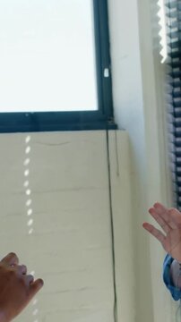 Vertical video: Seeing VR prompt, man in blue top with VR headset gesturing at work near blinds