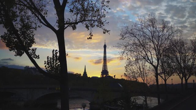 Paris Eiffel Tower between trees and river at sunset